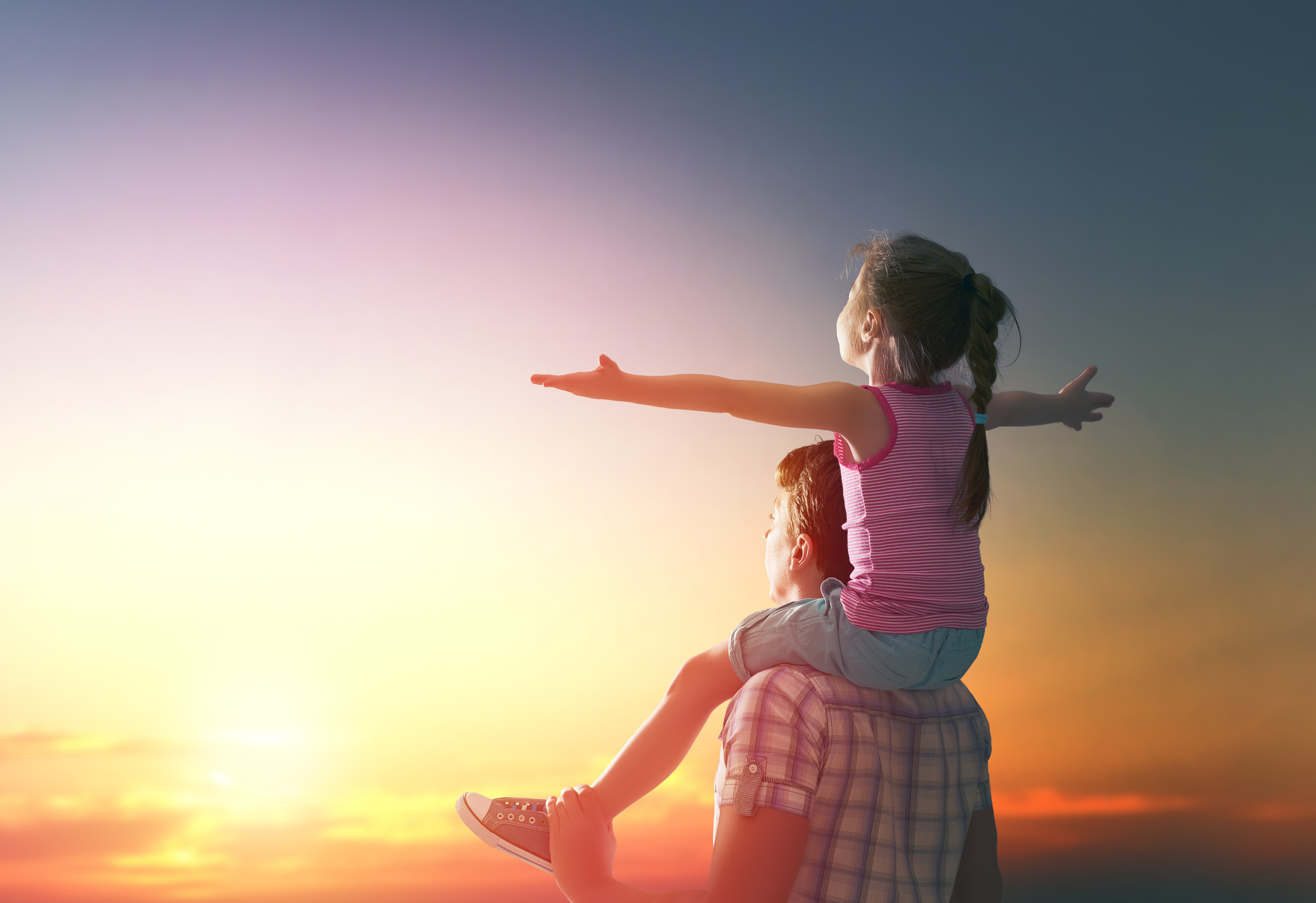 happy family at sunset. father and daughter having fun and playing in nature. the child sits on the shoulders of his father.